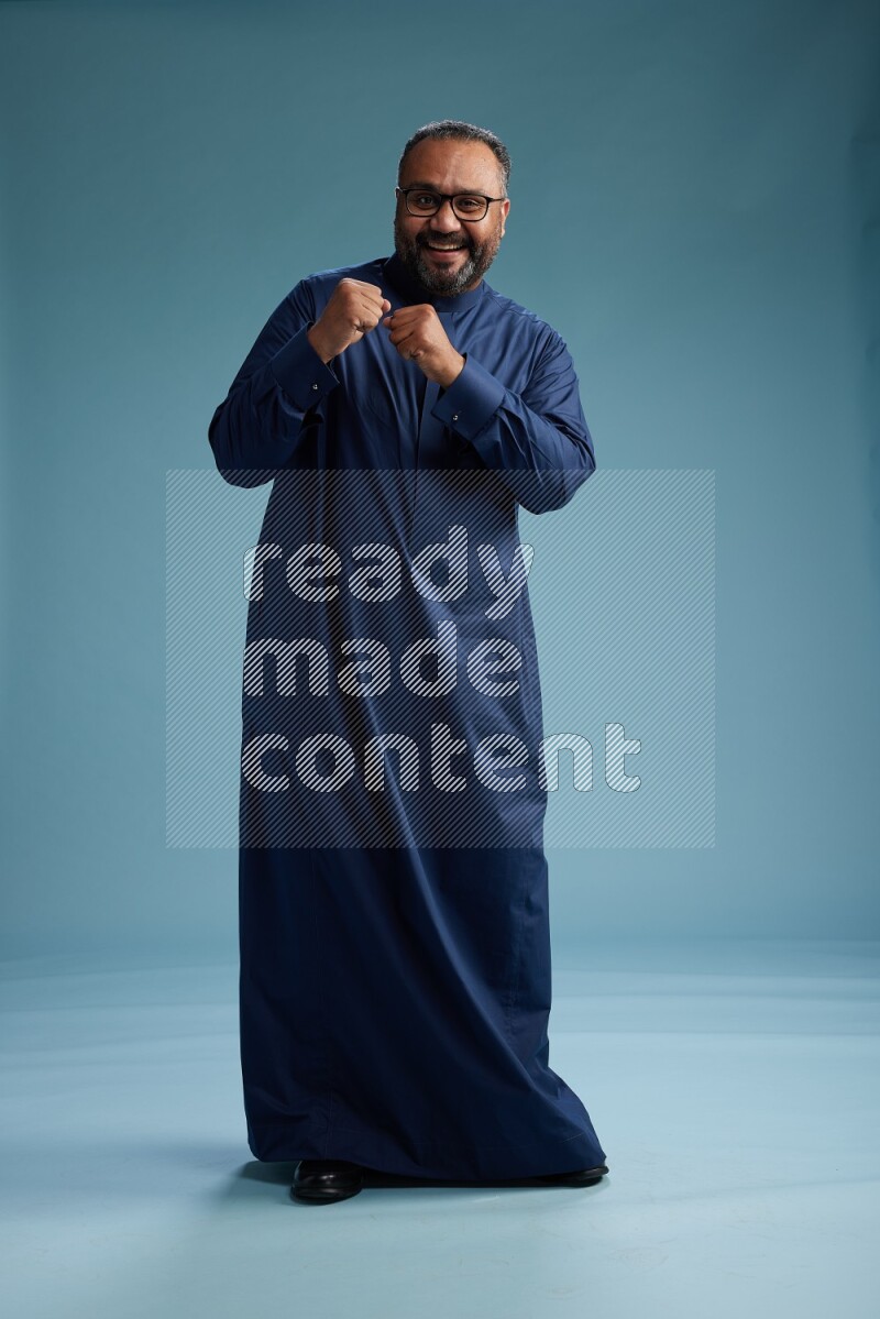 Saudi Man without shimag Standing Interacting with the camera on blue background