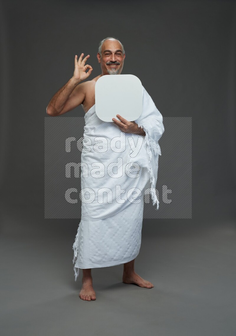 A man wearing Ehram Standing holding social media sign on gray background