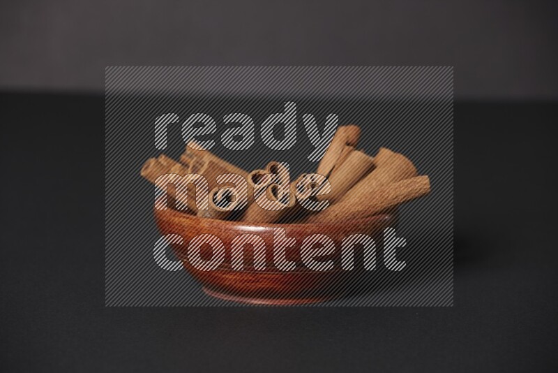 Cinnamon Sticks in a wooden bowl on black background