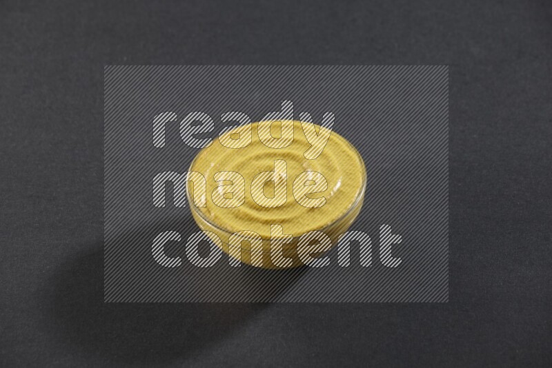 وعاء زجاجي ممتلئ بمعجون الخردل علي خلفية سوداء