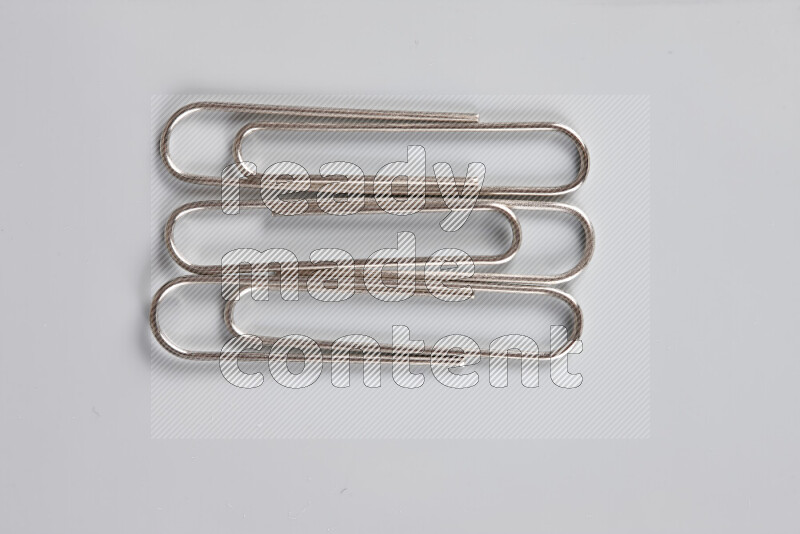 Silver paper clips isolated on a grey background
