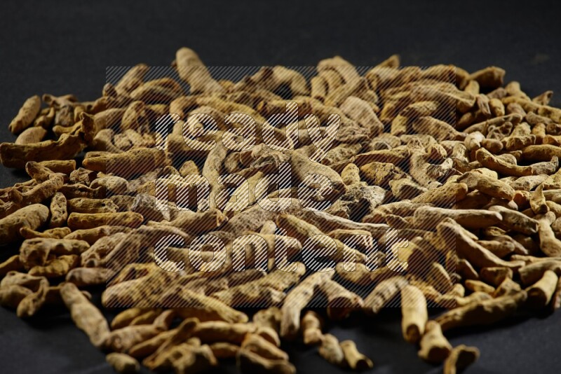 Dried turmeric fingers on black flooring