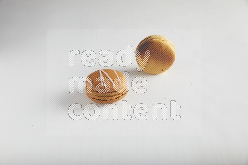 45º Shot of of two assorted Brown Irish Cream, and Yellow Crème Brulée macarons on white background