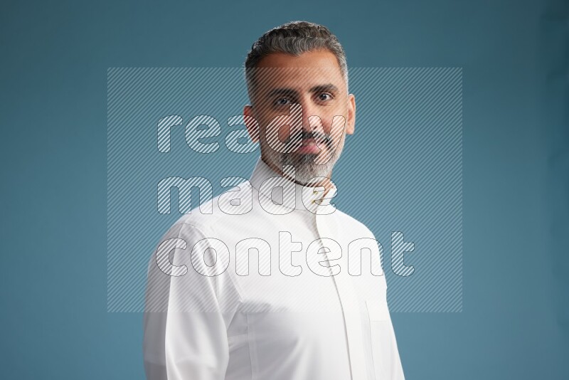 Saudi man waring thob posing to the camera on blue background