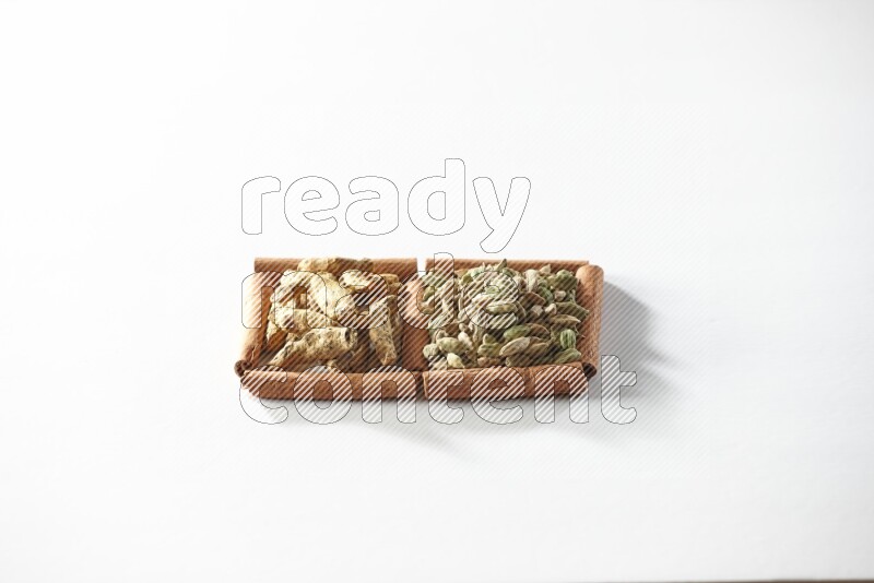 2 squares of cinnamon sticks full of cardamom and turmeric fingers on white flooring