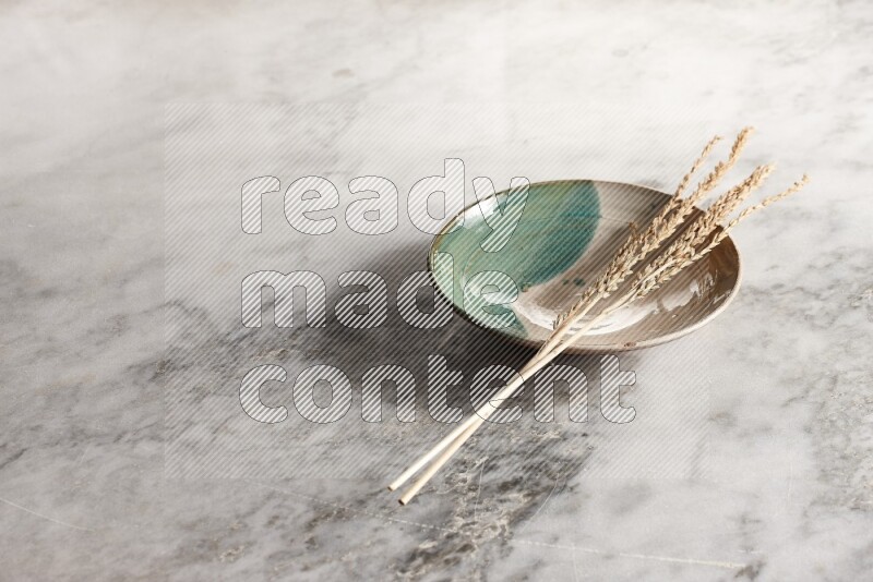 Wheat stalks on multicolored pottery plate on grey marble background