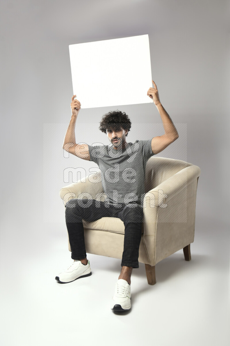 A man wearing casual sitting on a chair holding a white board on white background