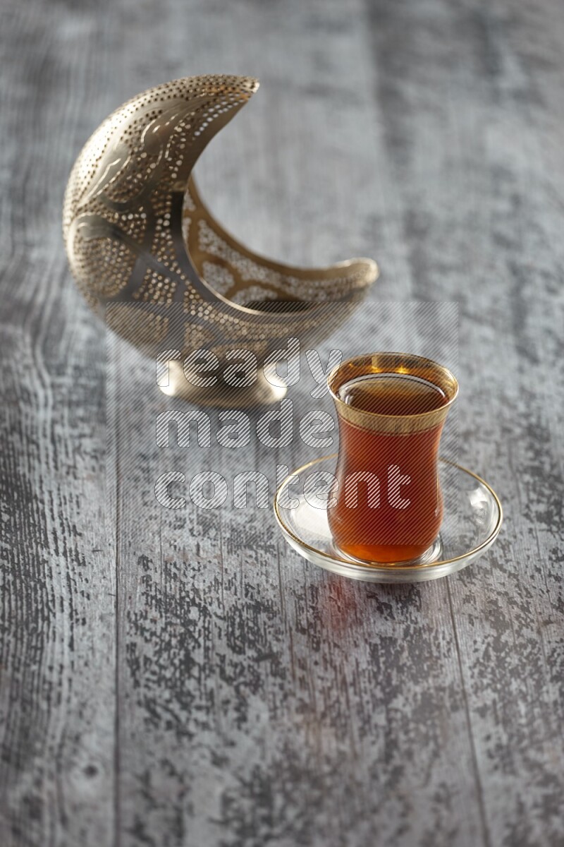 A silver lantern with different drinks, dates, nuts, prayer beads and quran on grey wooden background