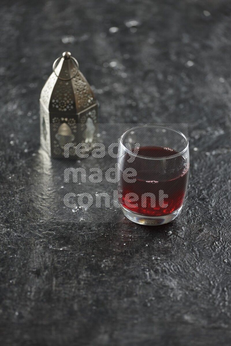 فانوس فضي مع مشروبات مختلفة وتمر ومكسرات وسبحة صلاة وقرآن على خلفية سوداء