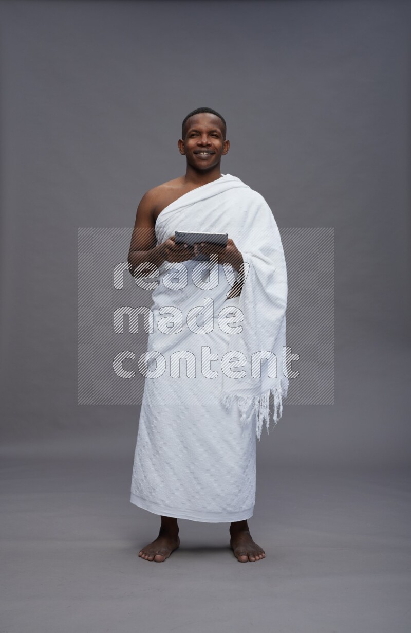 A man wearing Ehram Standing working on tablet on gray background