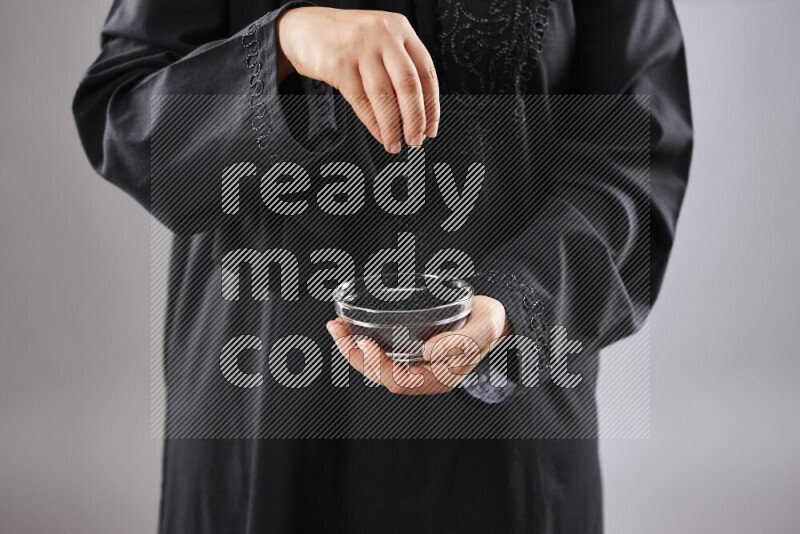 Woman in abaya holding different kinds of spices in different positions