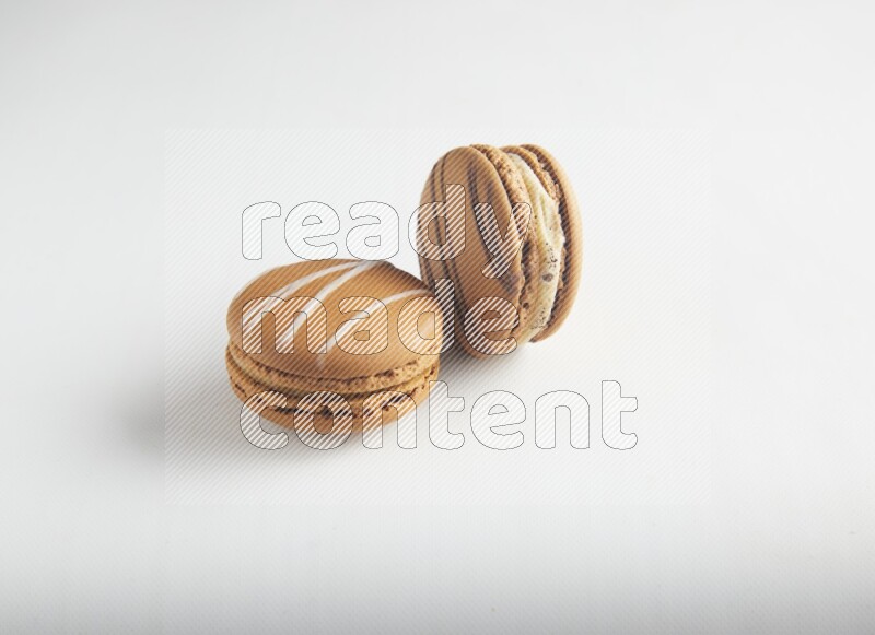 45º Shot of of two assorted Brown Irish Cream, and light brown  Almond Cream macarons on white background