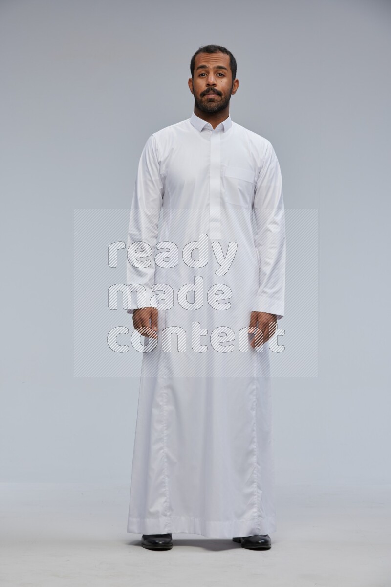 Saudi man Wearing Thob standing interacting with the camera on Gray background