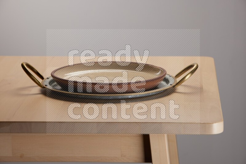 multicolored plate placed on a rounded stainless steel tray with golden handels on the edge of wooden table