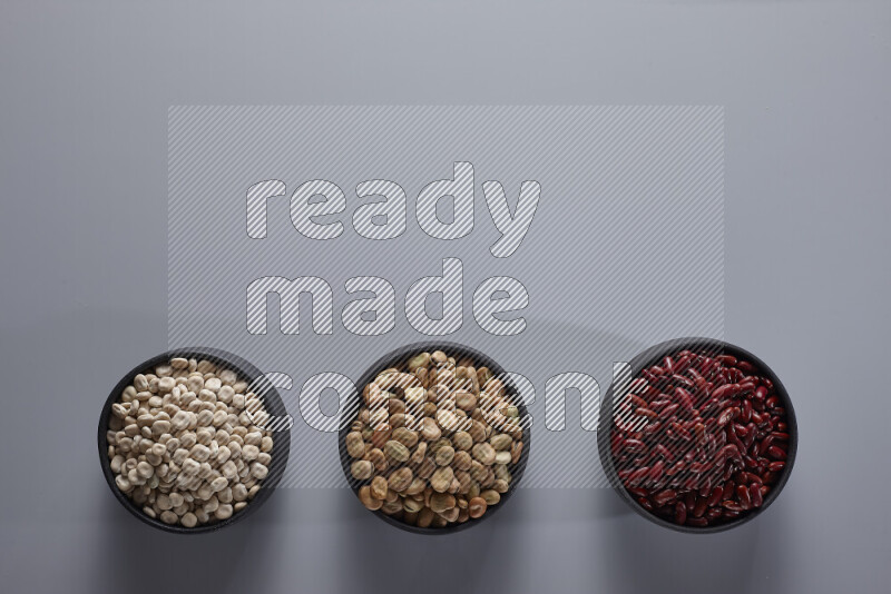 Legumes in pottery bowls on light grey background