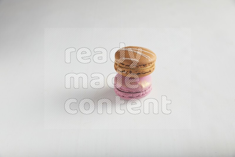 45º Shot of of two assorted Brown Irish Cream, and Purple Strawberry macarons on white background