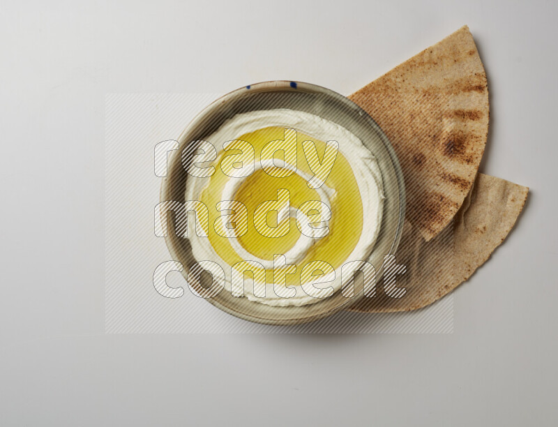 Lebnah garnished with olive oil in a grey pottery plate on a white background
