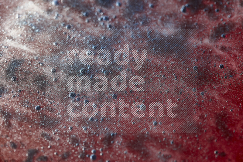 Close-ups of abstract blue watercolor drops on oil Surface on red background