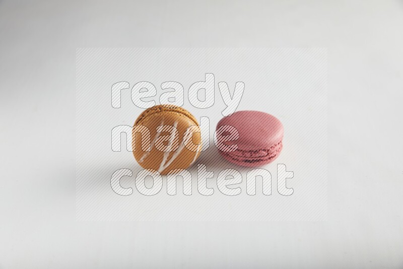 45º Shot of of two assorted Brown Irish Cream, and Pink Raspberry macarons on white background