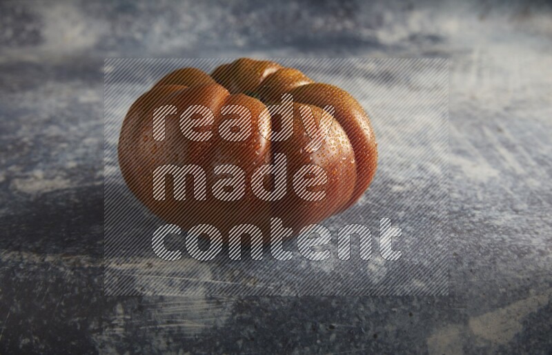 45 degree single heirloom tomato on a textured rustic blue background