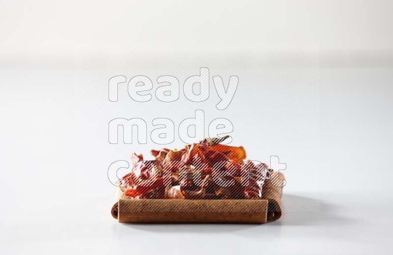 أربعة من أعواد القرفة مكونة شكل مربع بداخلها فلفل حار علي خلفية بيضاء