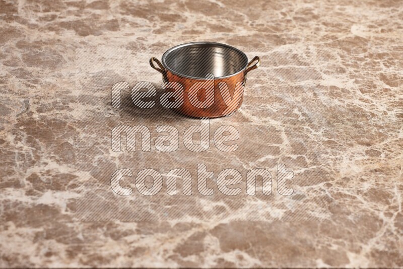 A small copper pot on beige marble background