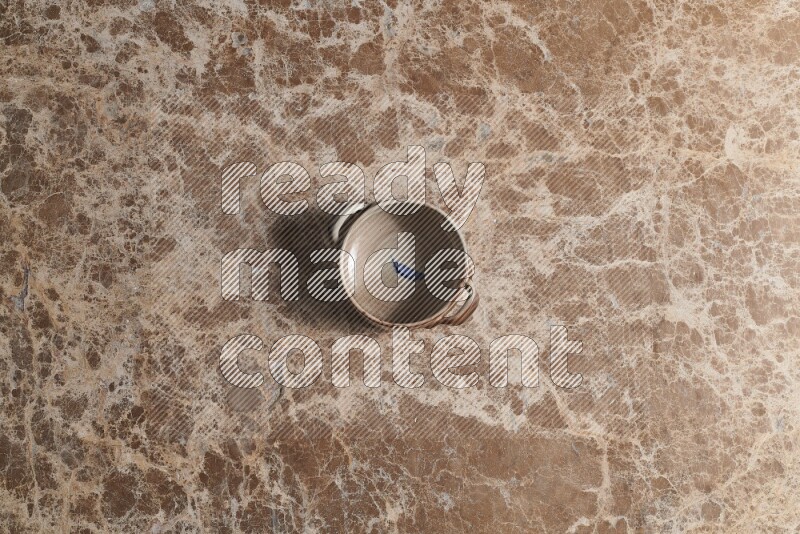 A multicolored pottery bowl on beige marble background