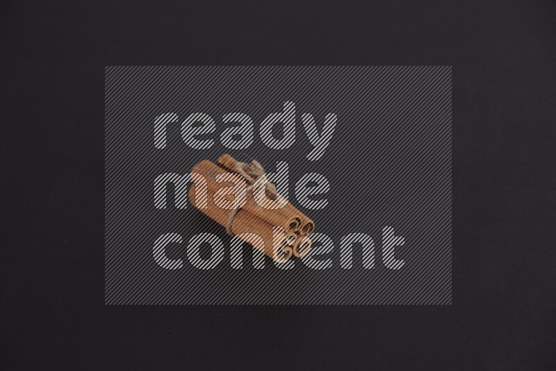 4 أعواد من القرفة مربوطة علي خلفية سوداء