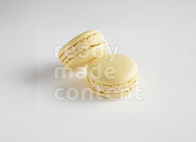 45º Shot of two Yellow Vanilla macarons on white background