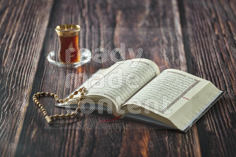 Quran with dates, prayer beads and different drinks all placed on wooden background