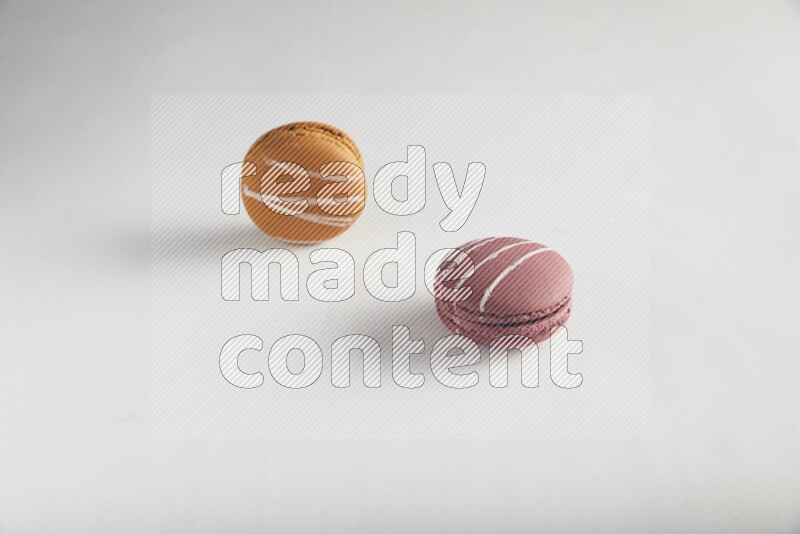 45º Shot of of two assorted Brown Irish Cream, and Red Poppy Flower macarons on white background