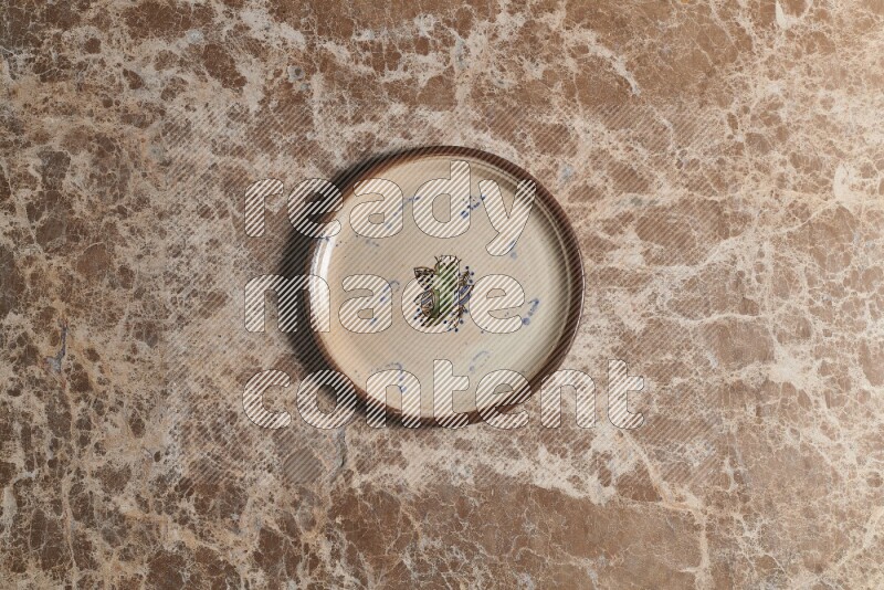 A decorative pottery plate on beige marble background