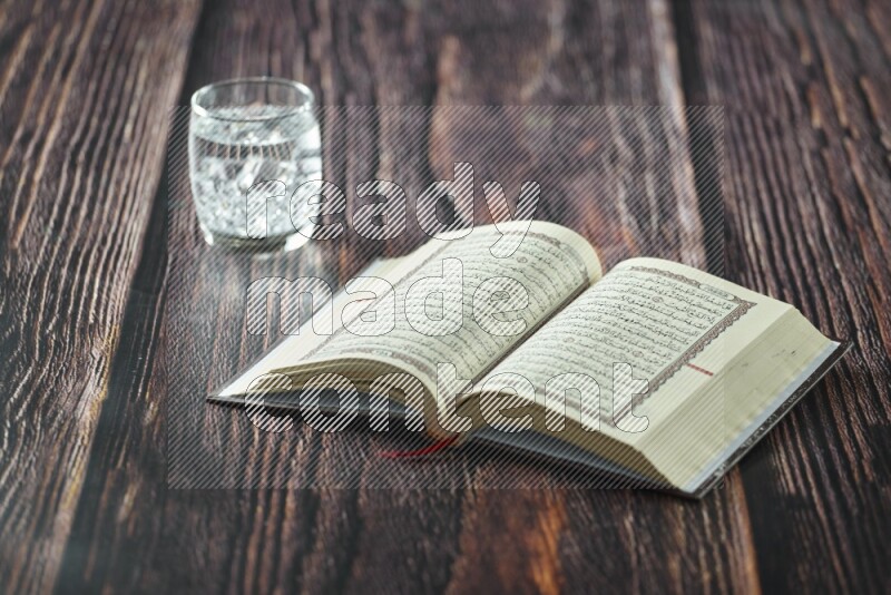 Quran with dates, prayer beads and different drinks all placed on wooden background