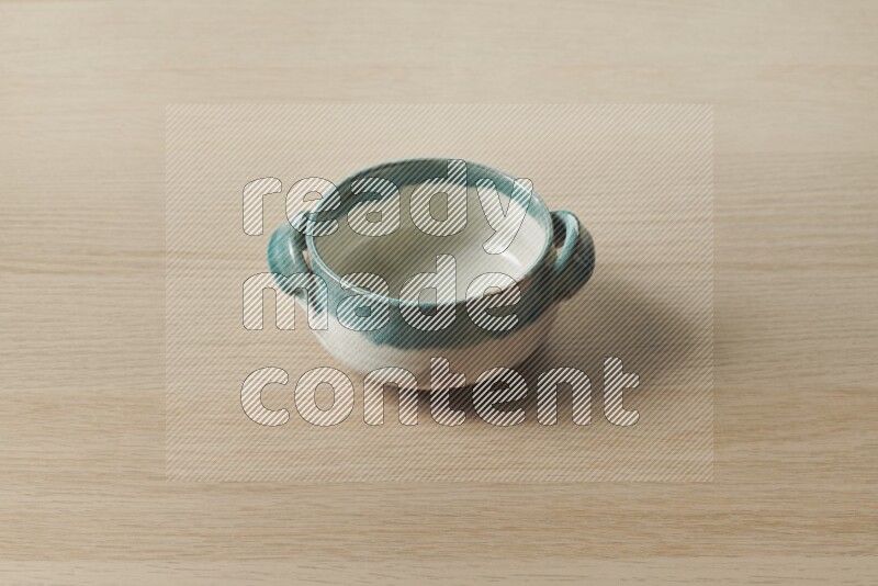 A multicolored pottery bowl on light wooden background