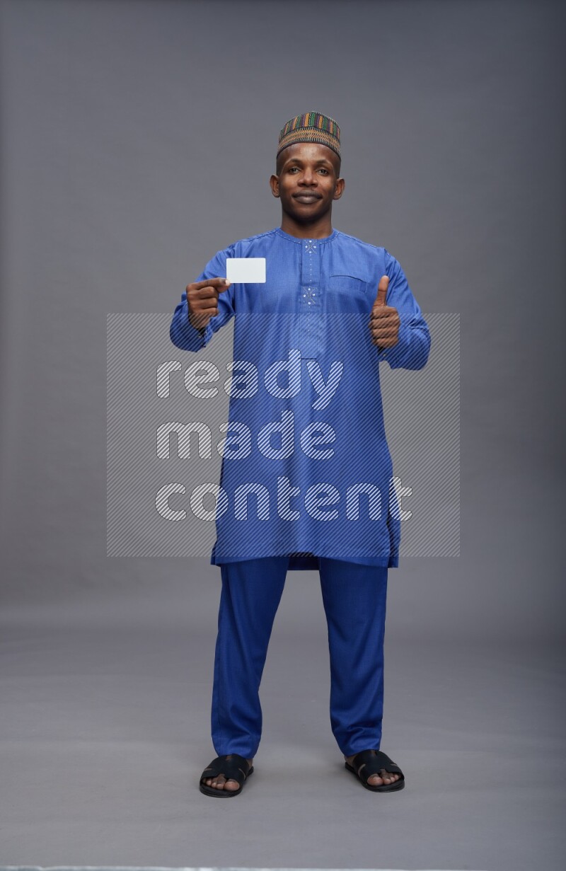 Man wearing Nigerian outfit standing holding ATM card on gray background