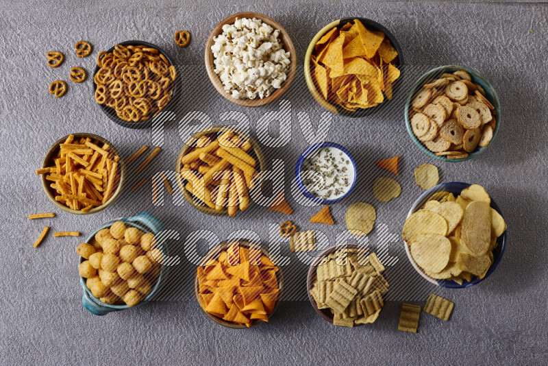 Assorted snacks in pottery bowls on grey background