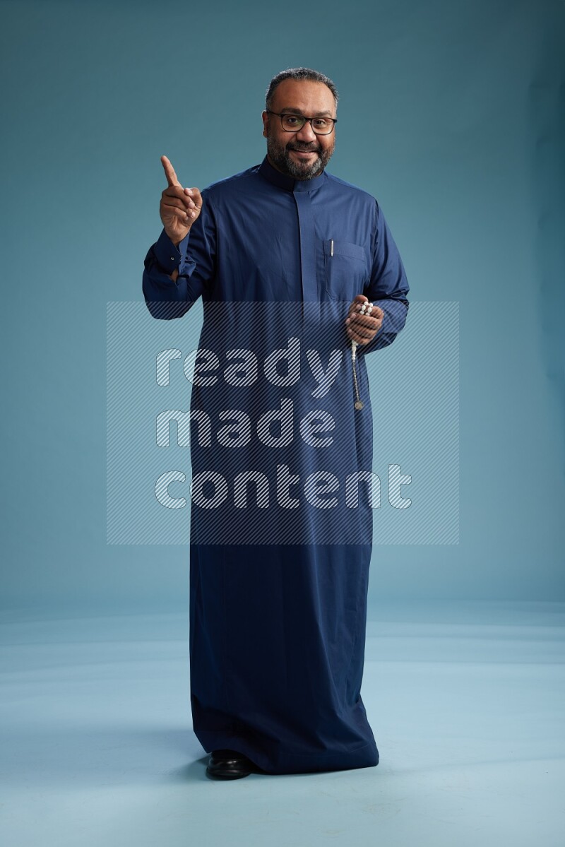 Saudi Man without shimag Standing Interacting with the camera on blue background