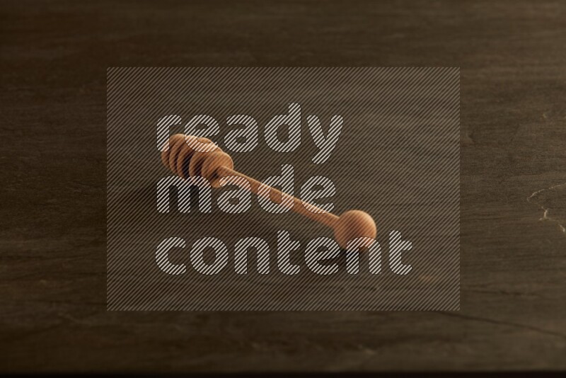 Wooden honey dipper on black slate background