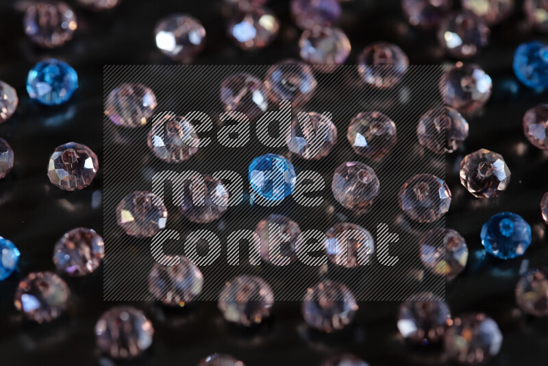 Rose and blue transparent crystal beads scattered on a black background