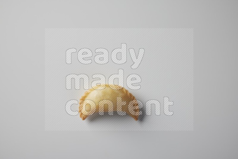 One fried sambosa from a top angle on a white background
