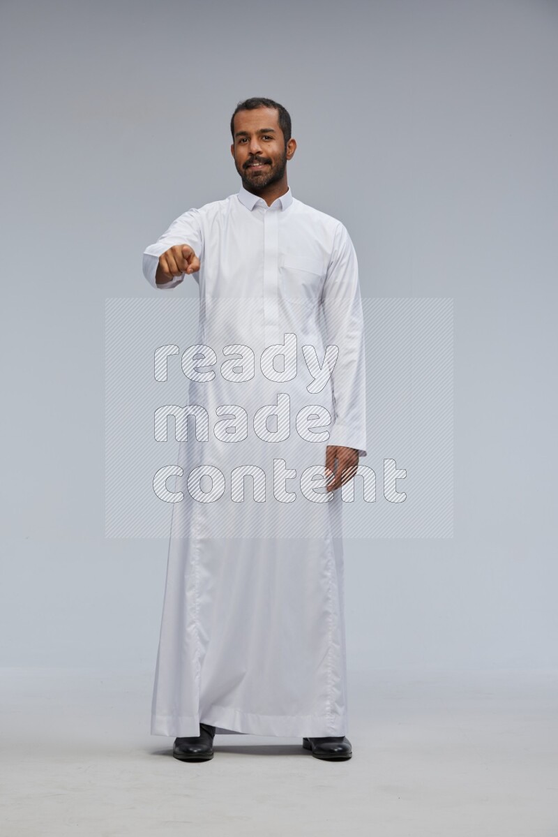 Saudi man Wearing Thob standing interacting with the camera on Gray background