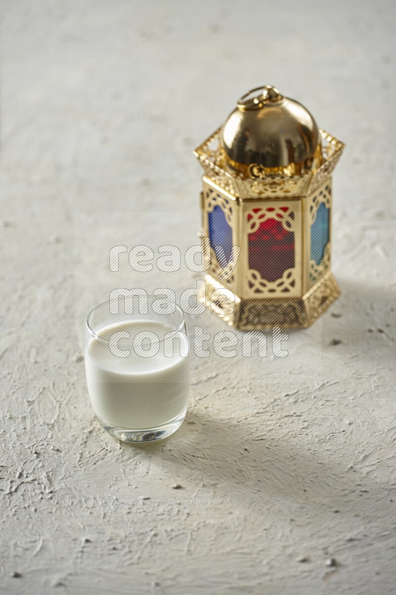 A golden lantern with different drinks, dates, nuts, prayer beads and quran on textured white background