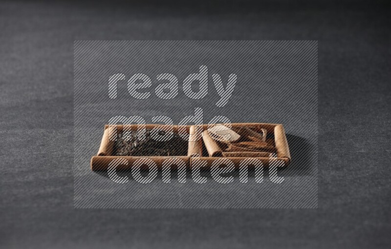 مربعان من أعواد القرفة ممتلئان بالشاي والقرفة علي خلفية سوداء