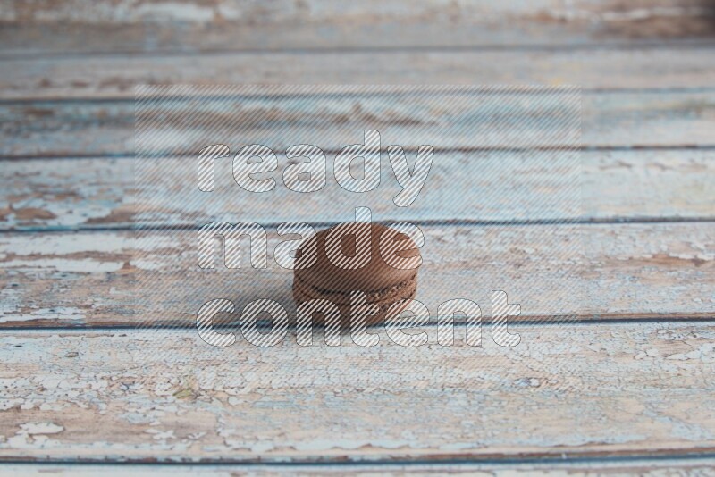 45º Shot of Brown Dark Chocolate macaron on light blue wooden background
