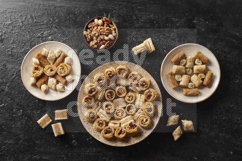 Oriental sweets in pottery plates with nuts in a dark setup