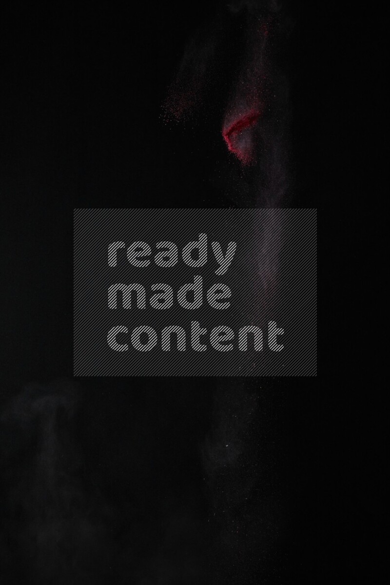 A side view of red powder explosion on black background