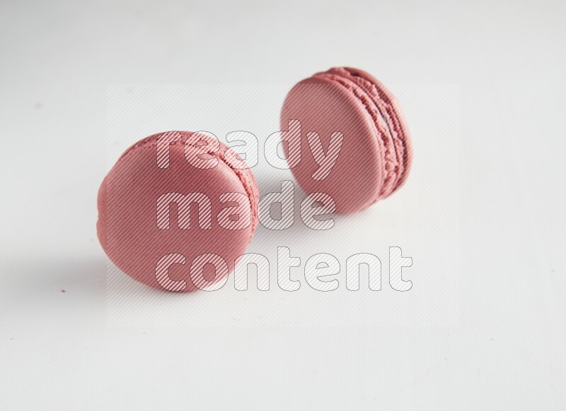 45º Shot of two Pink Raspberry macarons on white background