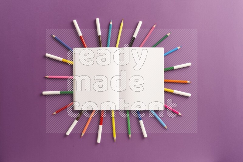 دفتر فارغ مفتوح مع مستلزمات مدرسية على خلفية أرجوانية