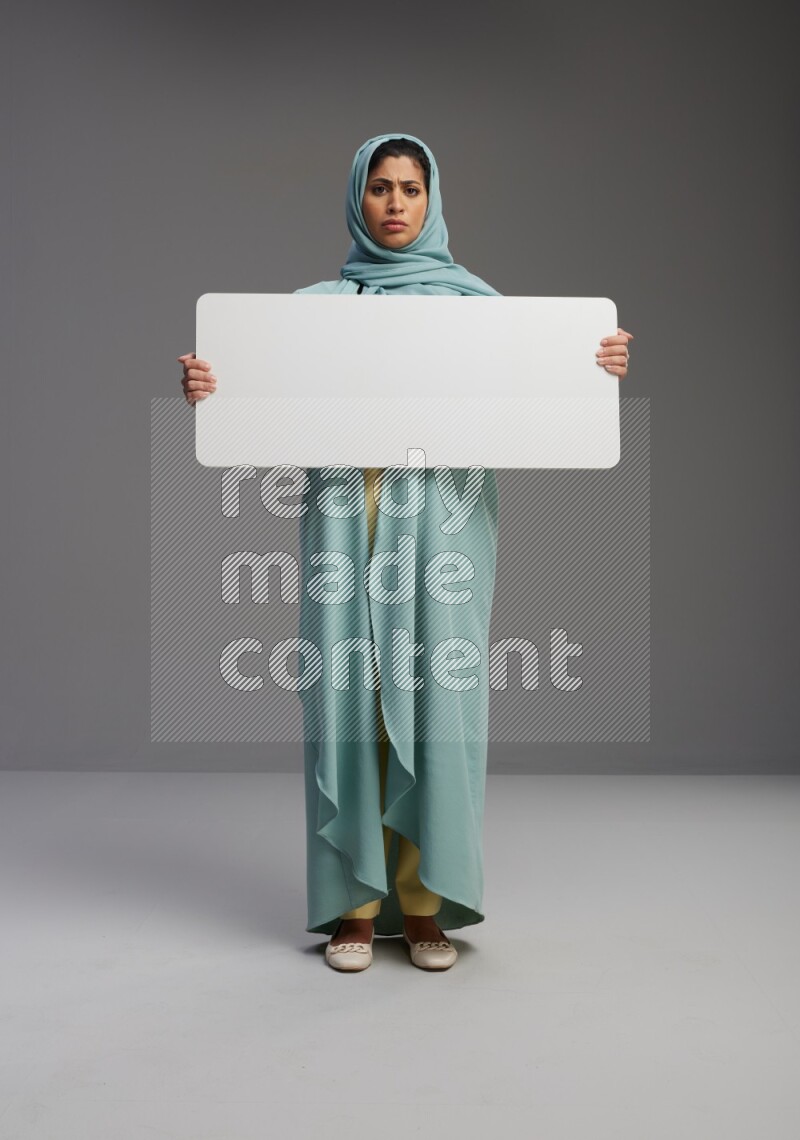Saudi Woman wearing Abaya standing holding board on Gray background