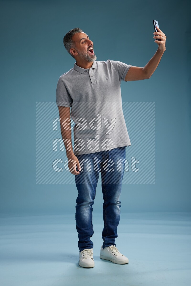 Man Standing taking selfie on blue background